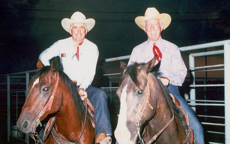 Foto antigua de dos vaqueros a caballo por la noche.